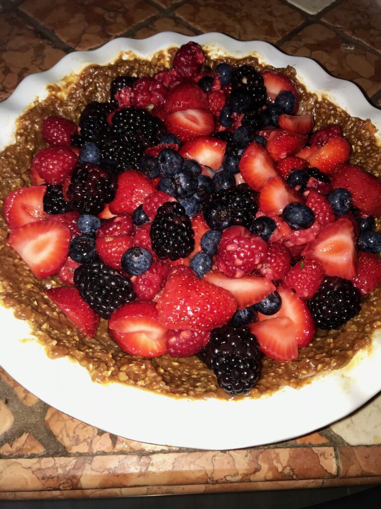 Pie with blackberries, strawberries, blueberries that has a walnut and date crust.