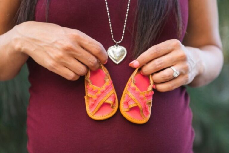 A pregnant woman holding two baby shoes - symbolizing the anticipation of motherhood. Image related to 'New Findings on Antidepressant Use During Pregnancy'.